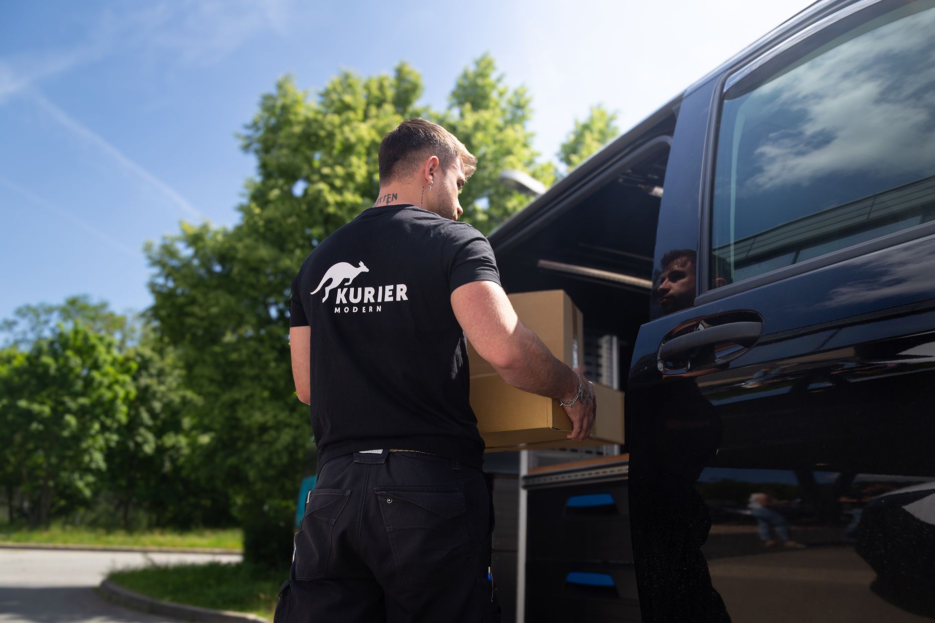 KurierModern-Kurier belädt ein Fahrzeug mit einem Paket